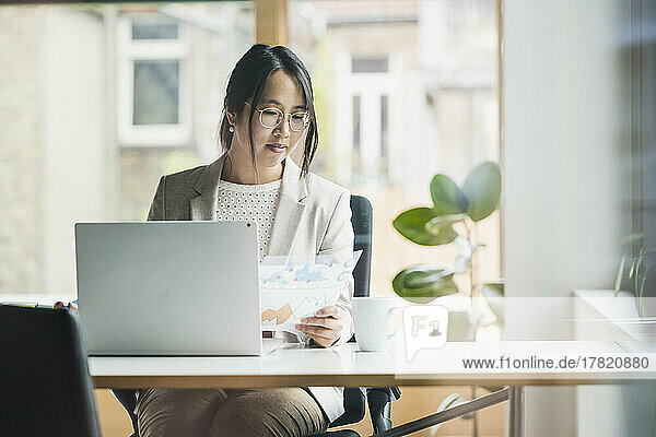Businesswoman with document sitting at desk