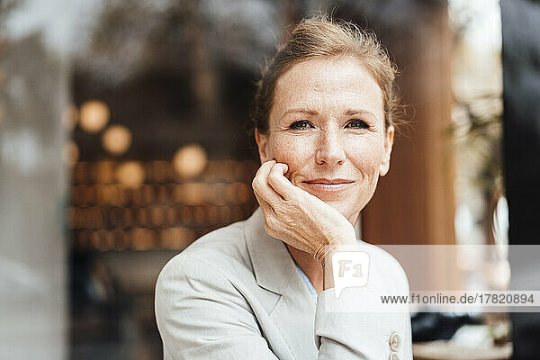 Lächelnde Geschäftsfrau mit Kopf in der Hand im Café