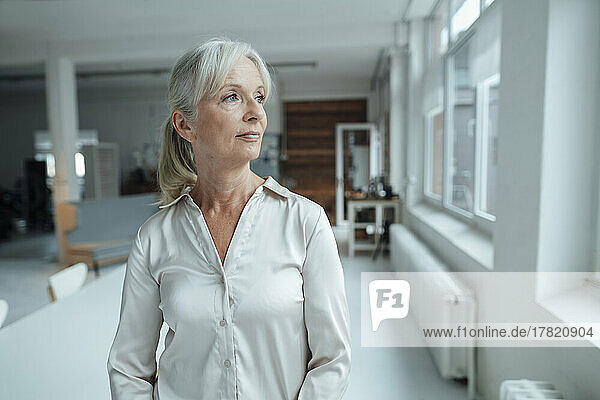 Thoughtful senior businesswoman standing in office