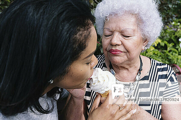 Mother sharing ice cream with daughter in park