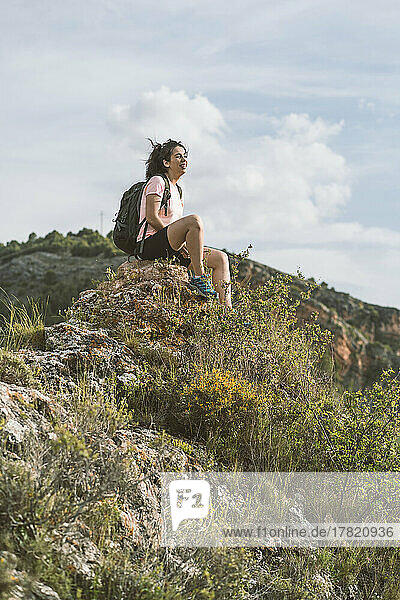 Glückliche Frau mit Rucksack sitzt auf einem Felsen in Aragon  Spanien