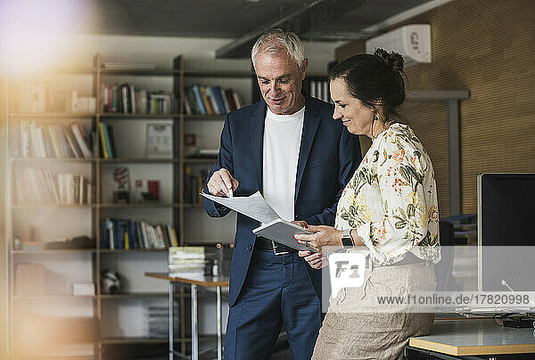 Mature businesswoman with colleague discussing over document in office