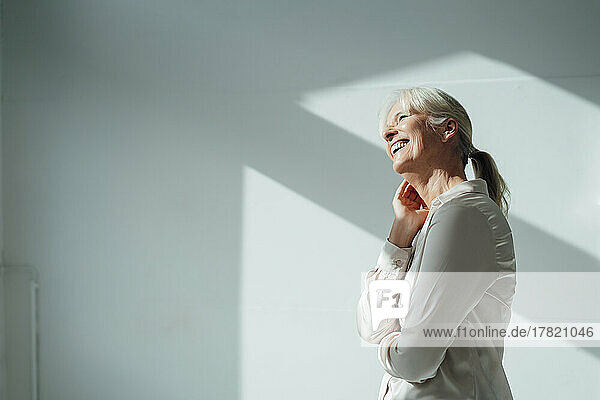 Happy businesswoman in front of wall in office