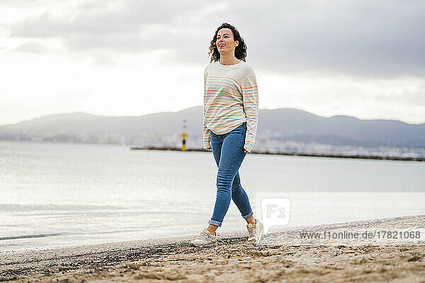 Lächelnde reife Frau  die am Strand spaziert