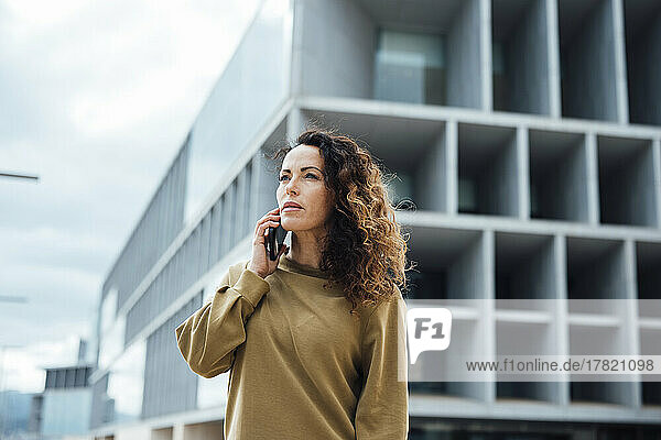 Businesswoman talking on mobile phone in front of office building