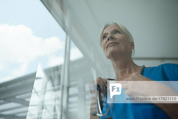 Thoughtful nurse with stethoscope at the window