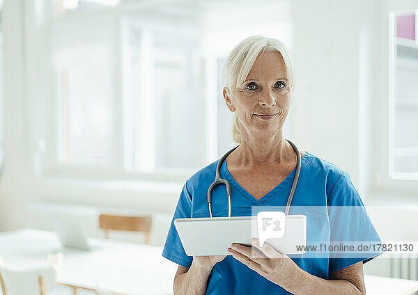 Smiling senior doctor holding tablet PC