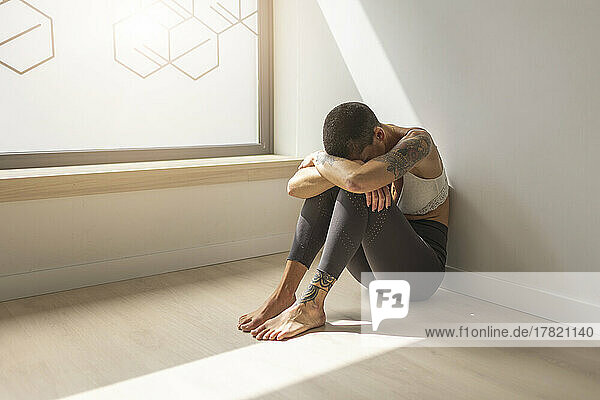 Traurige Frau sitzt auf dem Boden am Fenster