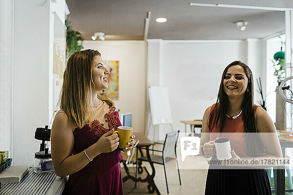 Happy businesswoman having coffee with colleague in office