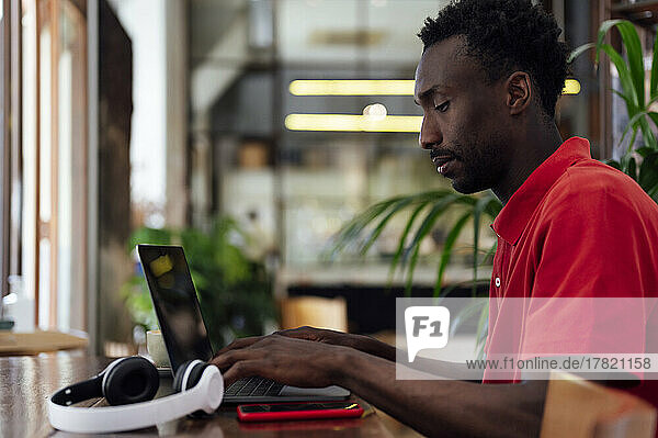 Man typing on laptop sitting at coffee shop