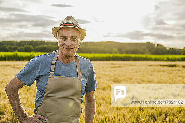 Lächelnder Bauer mit Schürze steht auf dem Bauernhof