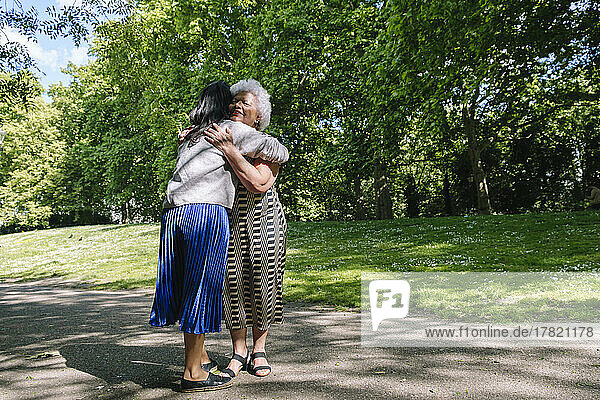 Mother hugging daughter in park