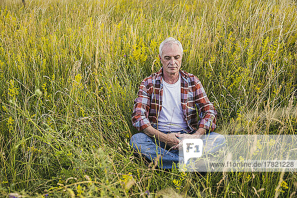 Farmer with eyes closed sitting amidst plants