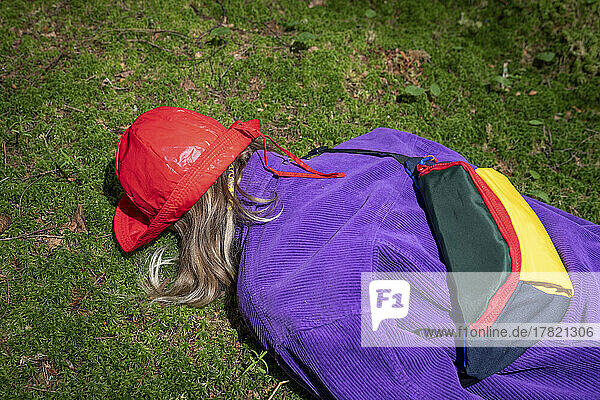 Woman wearing red bucket hat lying in forest