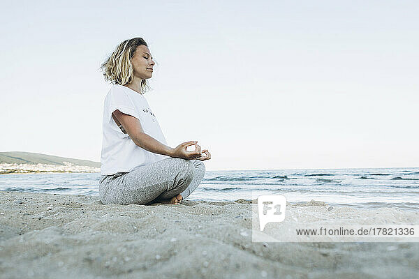 Woman with eyes closed doing yoga at beach