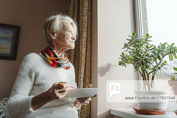 Senior woman with bowl by window
