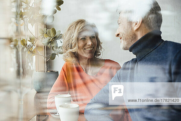 Smiling woman with man in cafe seen through glass