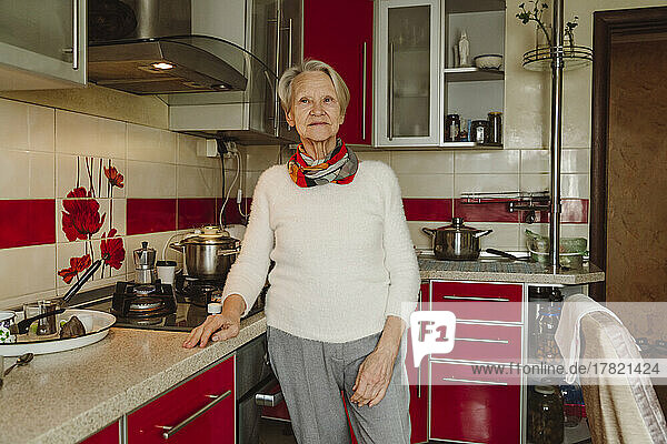 Smiling senior woman standing by kitchen counter