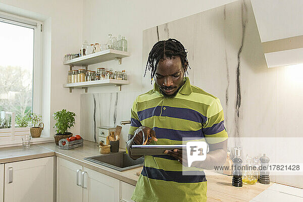 Man using tablet PC in kitchen