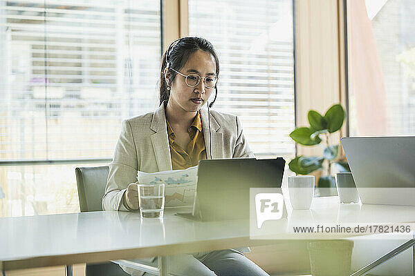 Businesswoman with headset working on tablet PC in office