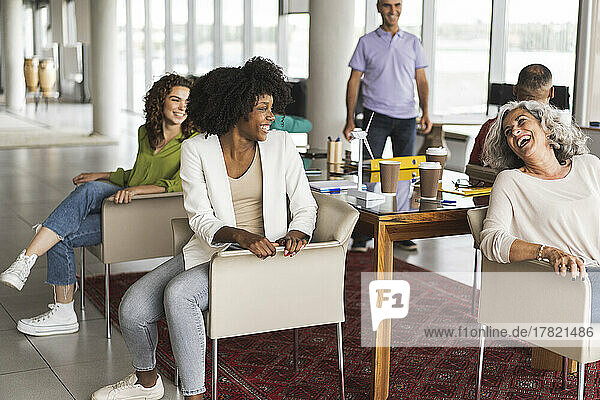 Glückliche Geschäftskollegen sitzen auf Stühlen im Büro
