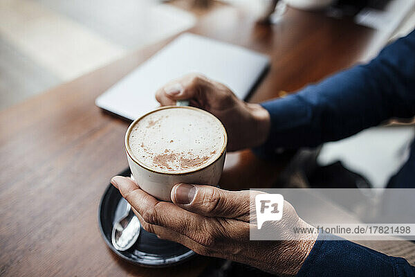Hands of man holding coffee cup in cafe