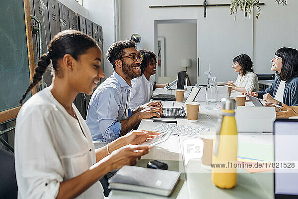 Zufriedene  gemischtrassige Geschäftskollegen  die am Schreibtisch im Coworking-Büro arbeiten