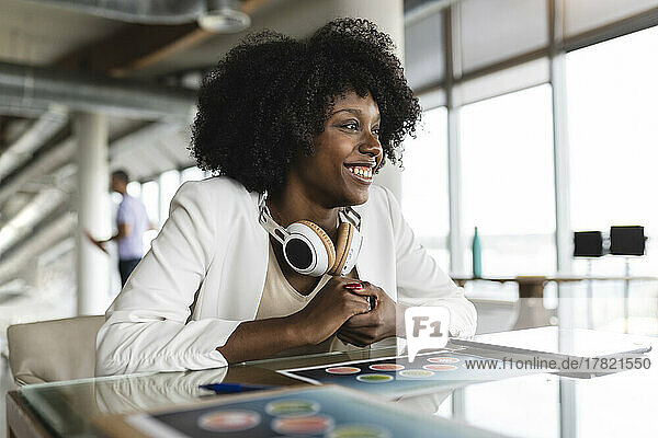 Businesswoman with wireless headphones sitting at desk