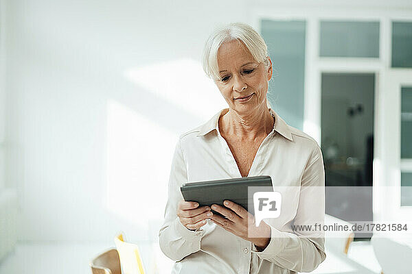 Senior businesswoman using tablet PC in office