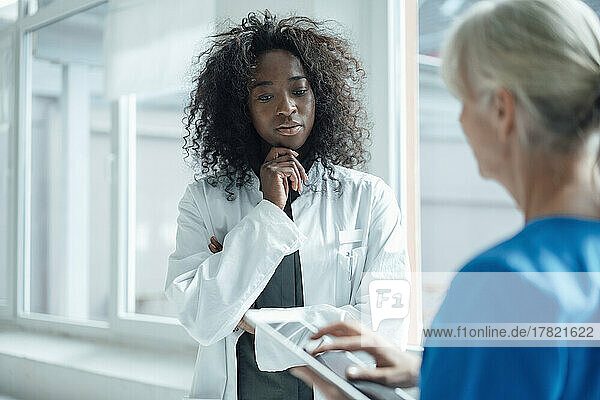 Nurse holding tablet PC talking with female doctor