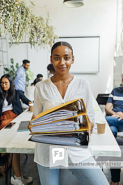 Young businesswoman holding files in office