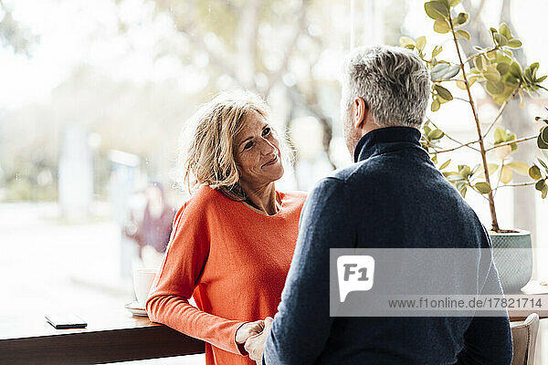 Lächelnde Frau im Gespräch mit Mann im Café