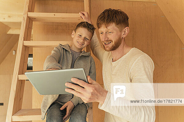 Father and son using tablet pc for creating home interior in eco wooden house