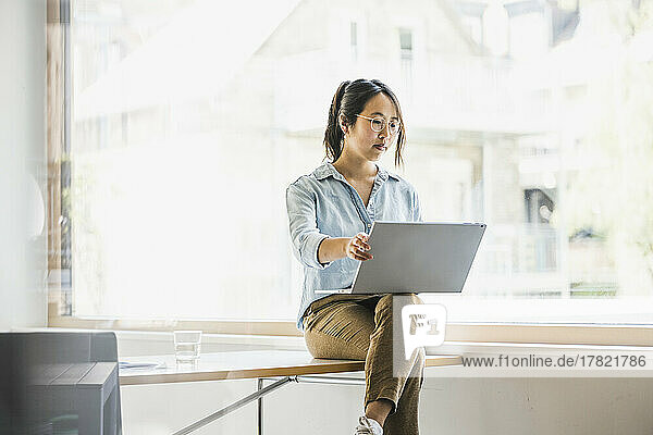 Geschäftsfrau arbeitet am Laptop am Fenster am Arbeitsplatz