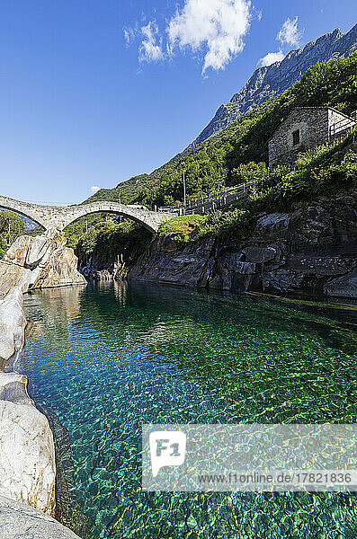 Switzerland  Ticino  Lavertezzo  Clear surface of Verzasca river with Ponte dei Salti arch bridge in background