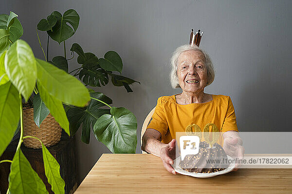 Glückliche ältere Frau  die zu Hause Geburtstag mit Kuchen feiert