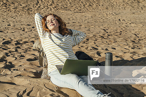 Frau mit Laptop entspannt sich an einem sonnigen Tag am Strand