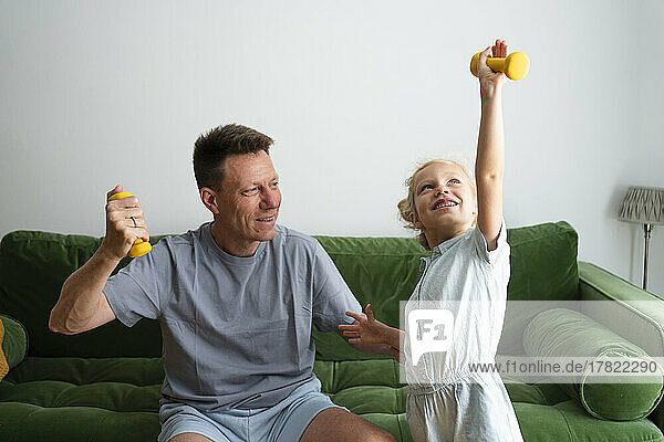 Father and daughter exercising with dumbbells at home