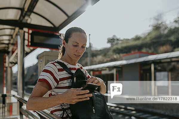 Woman using phone waiting at railroad station