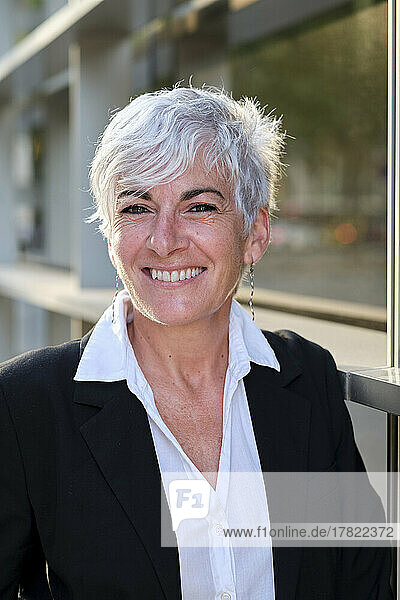 Smiling businesswoman with white hair near railing