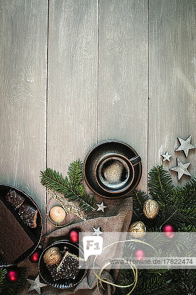 Studio shot of cup of coffee  twigs  walnuts  Christmas ornaments and gingerbread