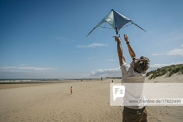 Mann lässt an einem sonnigen Tag am Strand Drachen steigen