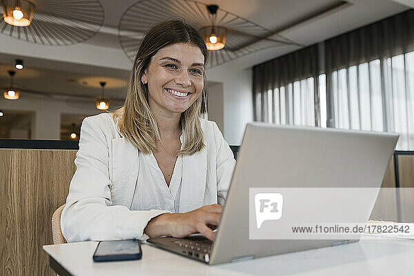 Smiling businesswoman using laptop at restaurant