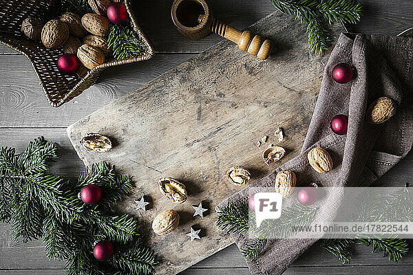 Studio shot of cutting board  star shaped wicker basket  twigs  Christmas ornaments  walnuts and simple nutcracker