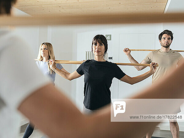 Engagierte Männer und Frauen praktizieren Stock-Yoga im Fitnessstudio