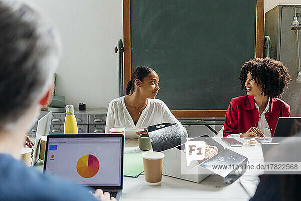 Geschäftsfrauen unterhalten sich am Schreibtisch im Coworking Space