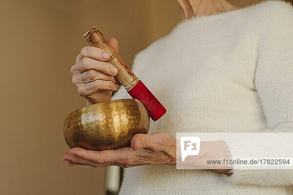 Hände einer älteren Frau  die eine Klangschale hält