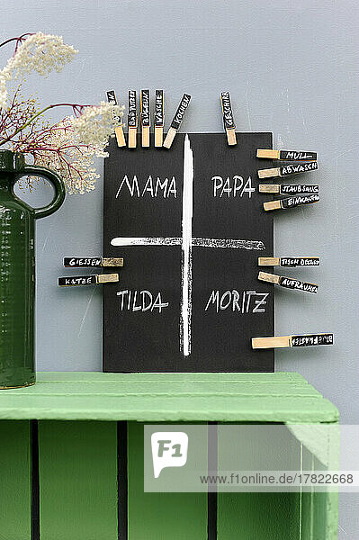 Studio shot of DIY chalkboard with cleaning duty plan divided by clothespin name tags