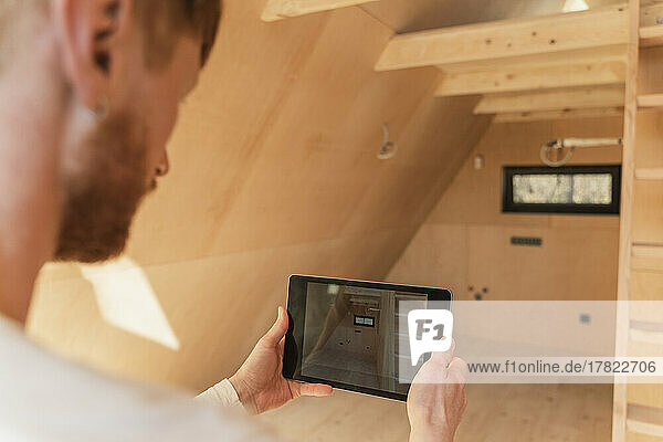 Man using tablet pc to visualise home interior at new wooden eco house