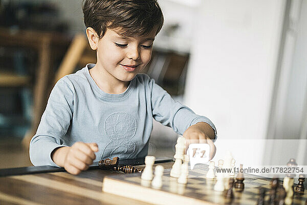 Smiling boy playing chess at home